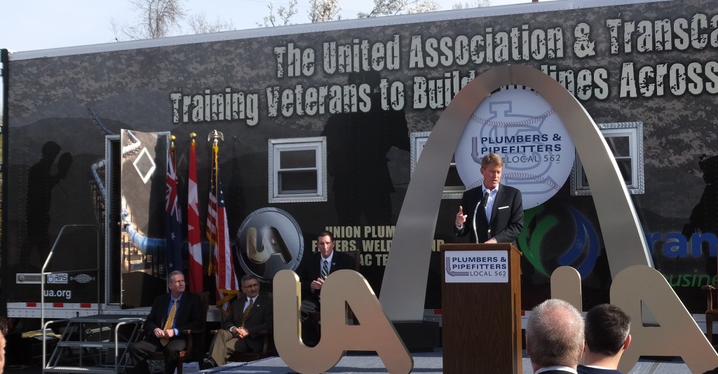 COMPLIMENTING the United Association of Plumbers & Pipefitters (UA) for their extraordinary Veterans In Piping (VIP) Program, Missouri Attorney General Chris Koster (at podium in front of the program’s training trailers) said “Any veteran struggling to find a steady job after serving our country is one too many.” Seated behind Koster are (from left to right): UA International Representative, St. Louis County Councilman and Local 562 member Mike O’Mara, TransCanada Director of Governmental Affairs Peter Jaskoski and Local 562 Business Manager John O’Mara. – Labor Tribune photo 